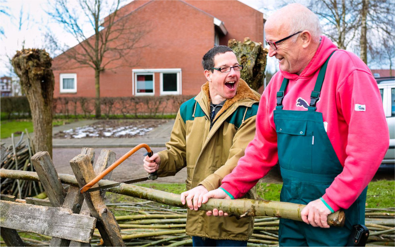 Medewerker en bewoner van Sovak werken in de tuin