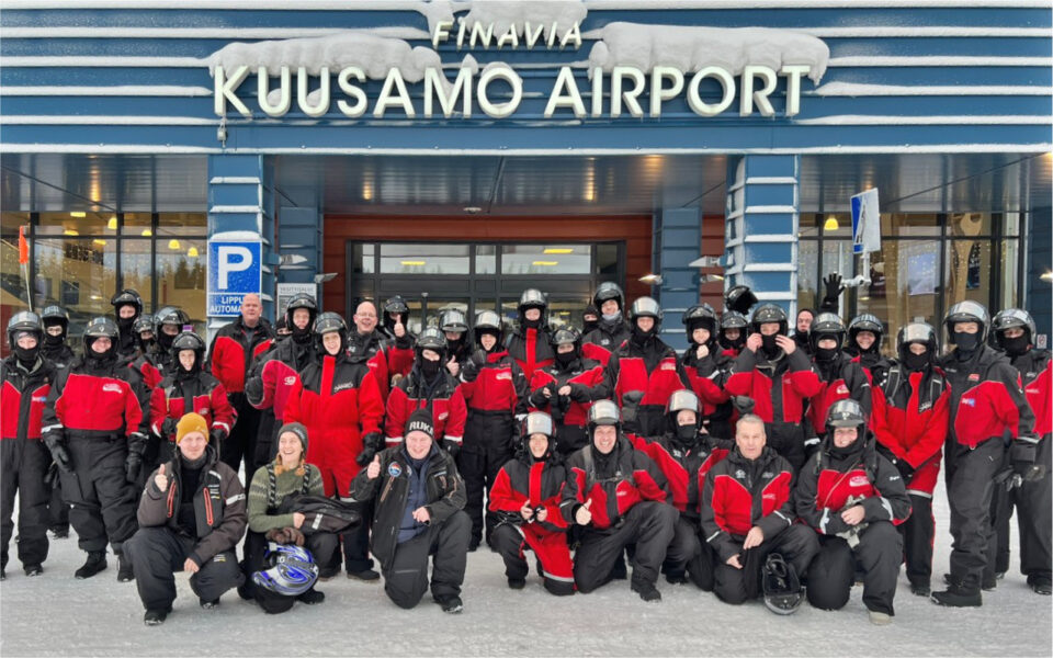 Het XIXO-team poseert in rode outdoor-kleren voor de ingang van Kuusamo Airport in Lapland