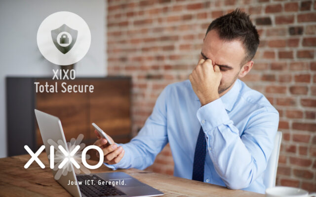 Man zit aan bureau in kantoor en bekijkt zijn smartphone