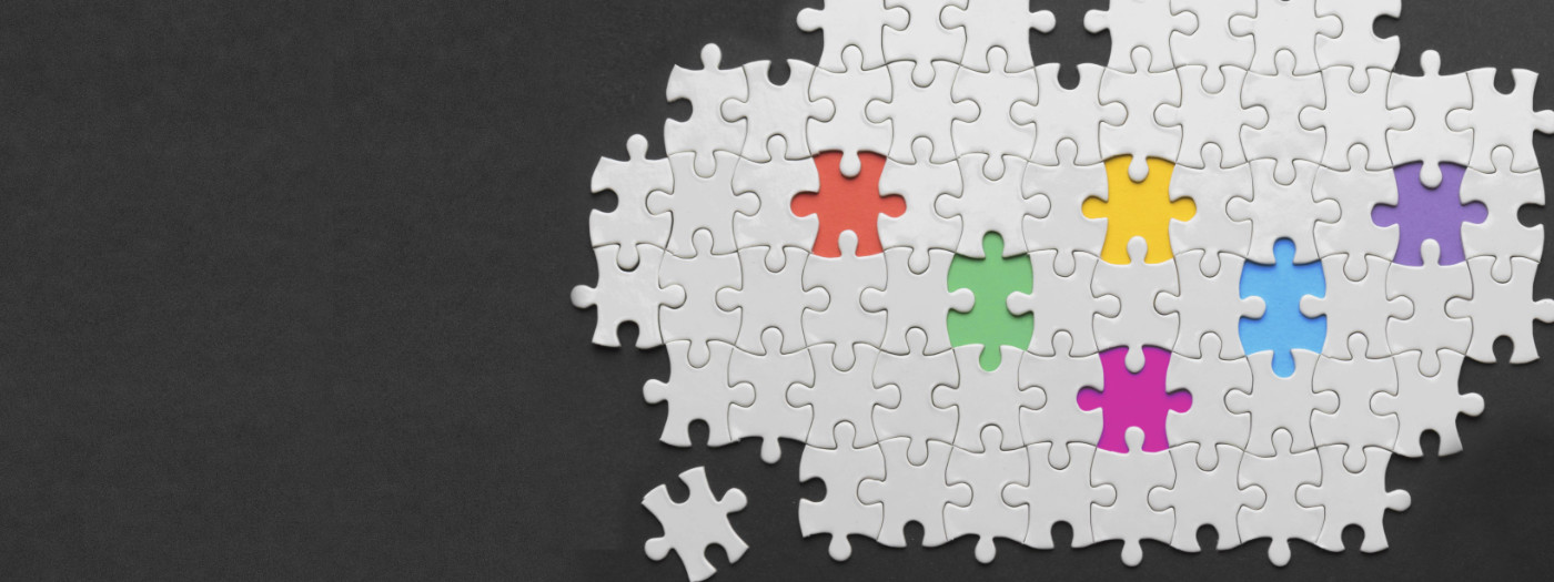 Witte puzzelstukjes op een zwarte achtergrond met daarin 6 gekleurde stukjes