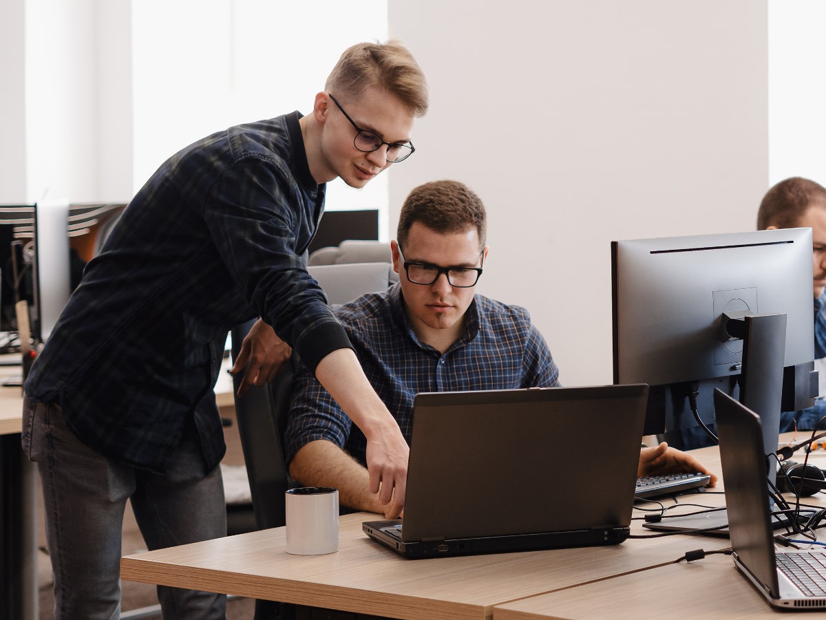 Medewerker wijst collega iets aan op beeldscherm